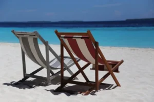 Lunes 16 de agosto cerrado por festivo en Blanes Seguros, anuncio de cierre con imagen de dos hamacas en la playa